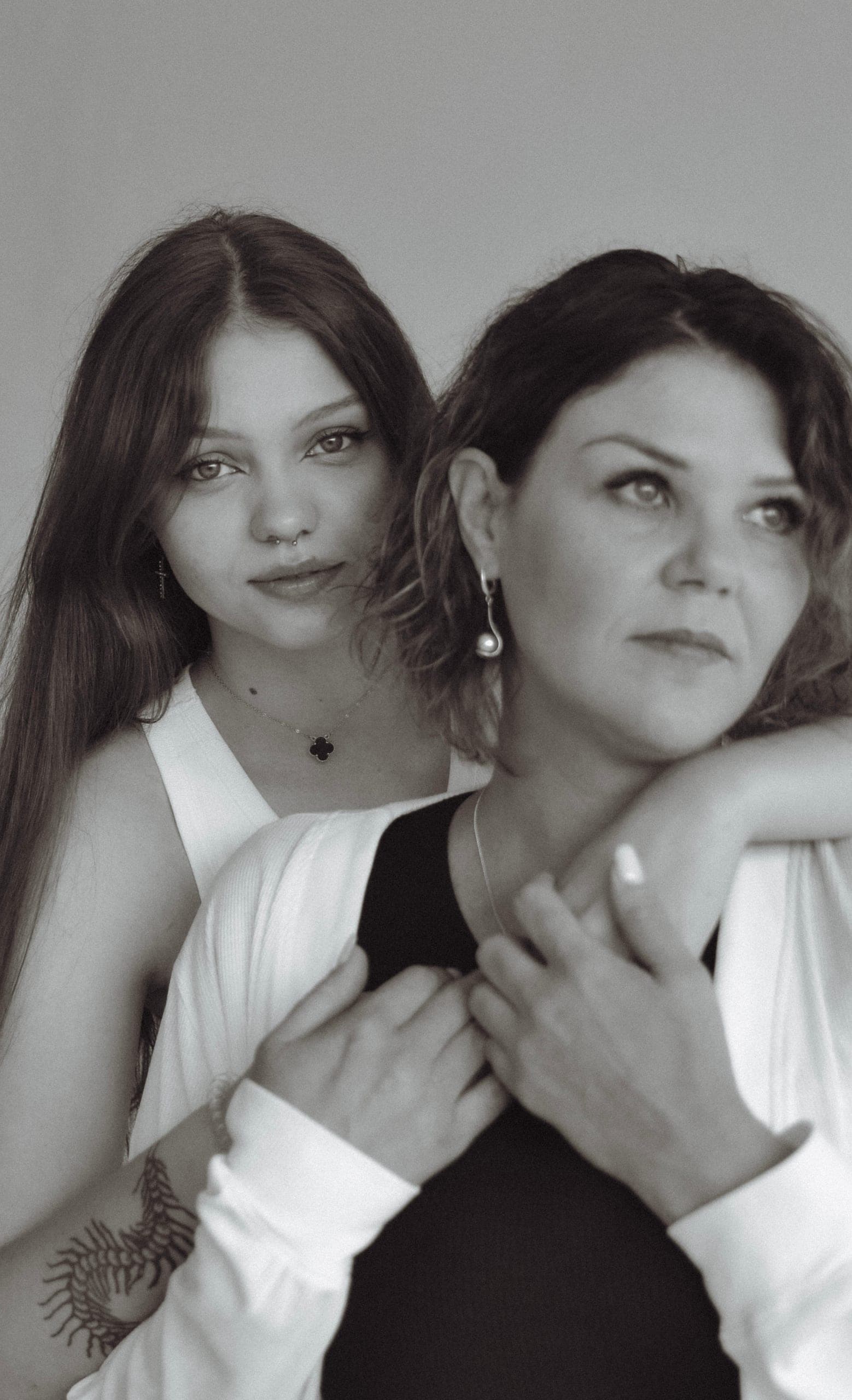 Nastoletnia córka obejmuje mamę od tyłu, obie patrzą w różne strony, czarno-biała sesja rodzinna