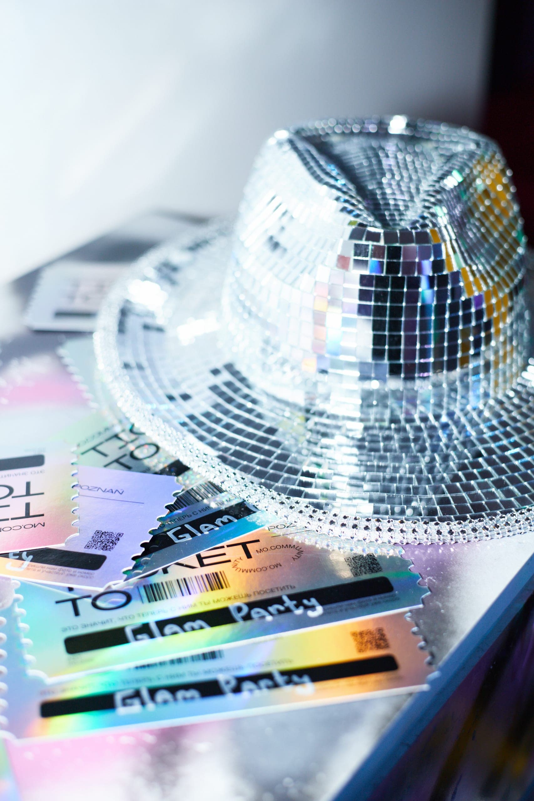 Lustrzany kapelusz disco i holograficzne bilety Glam Party na srebrnym stole, detal z imprezy